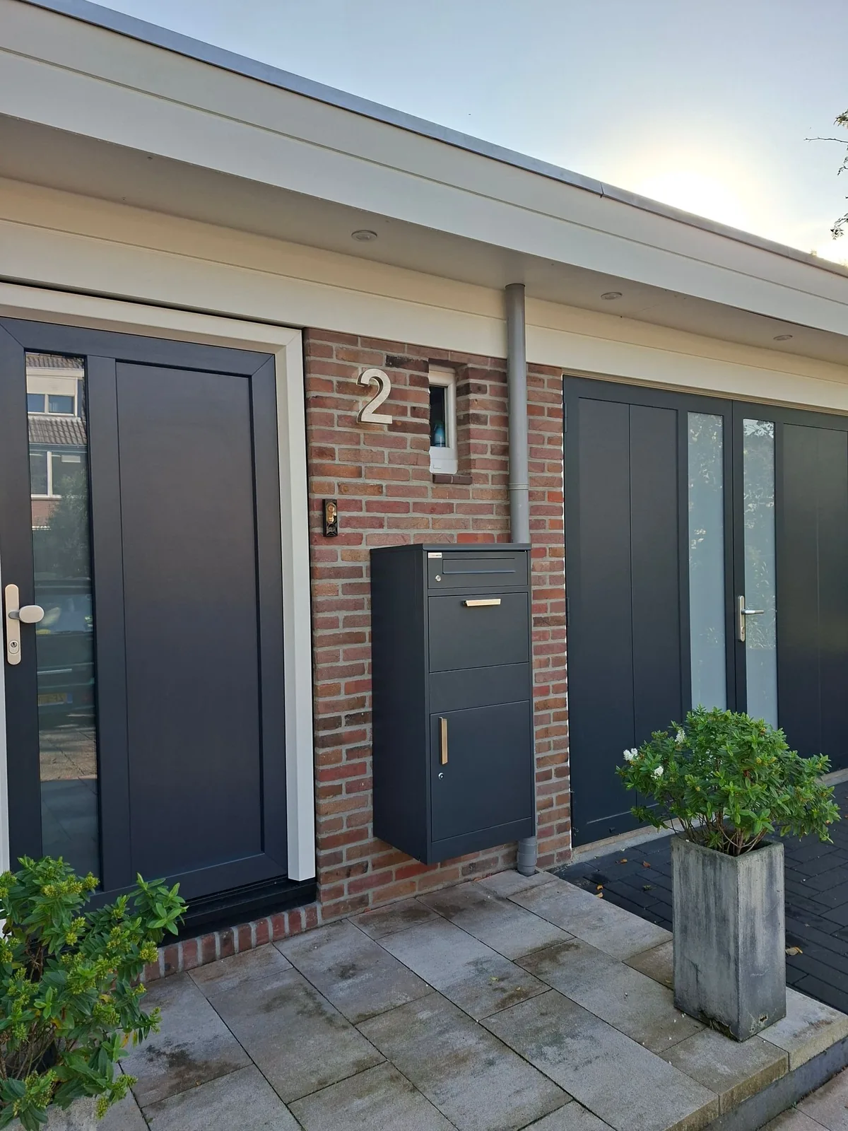 Pakketbrievenbus antraciet aan een bakstenen gevel naast de voordeur