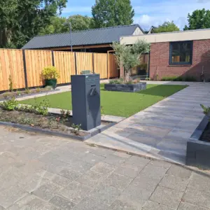 Vrijstaande pakketbrievenbus antraciet in een aangelegde voortuin